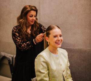 On-set hair and makeup artist preparing talent for corporate filming